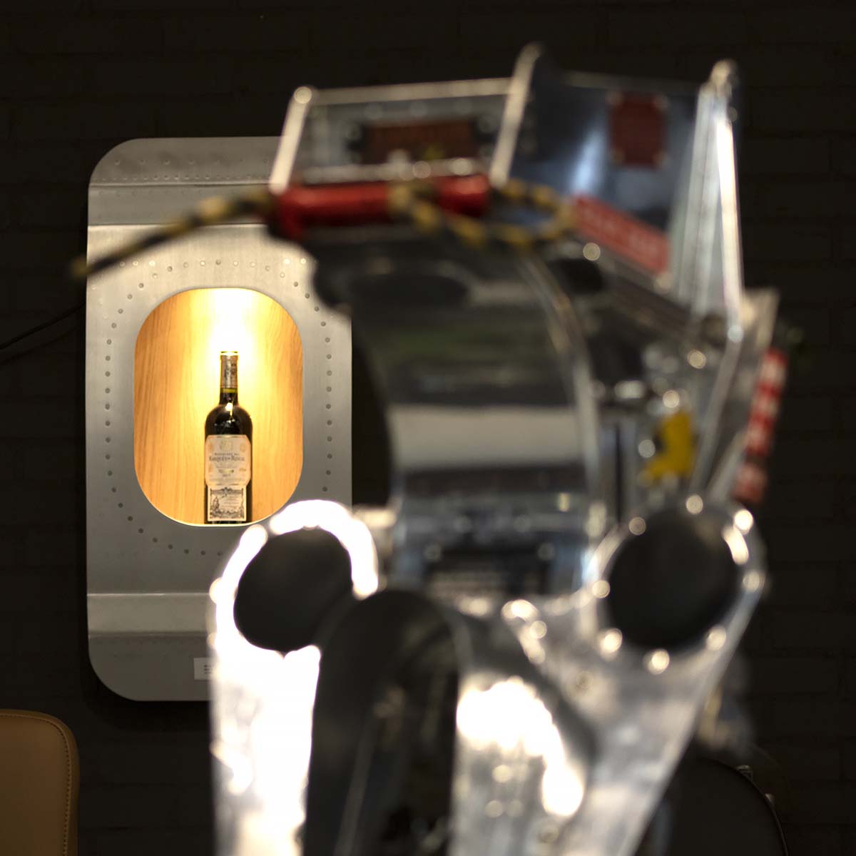 Aircraft window section wall bar hanging on a wall behind a mirror-polished ejection seat.