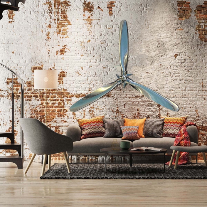 Polished Hartzell propellers and hub hanging on a brick wall in an industrial style living room.