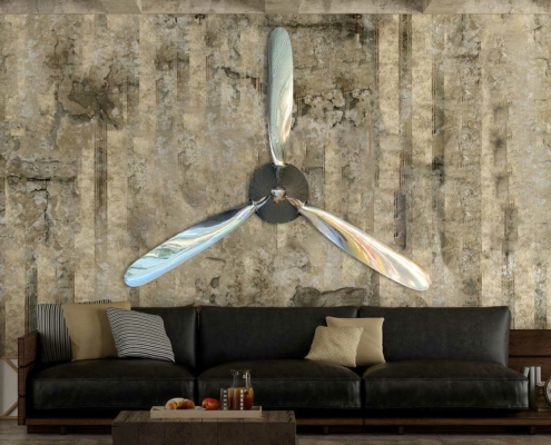 Polished three-bladed Hartzell propeller with spinner mounted on a wall in a grunge living room.