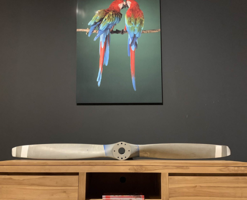 Second hand two-bladed Sensenich propeller lying on a brown cabinet.